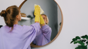 Professional NDIS cleaner wiping a living room mirror